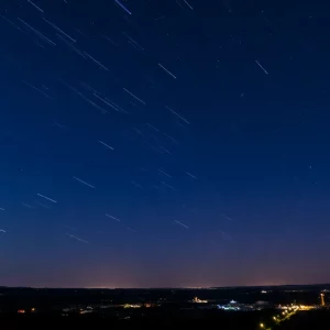 Starry night sky over Charleston with meteor streaks.